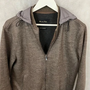 Brun jacka med huva från Massimo Dutti - Snygg brun jacka från Massimo Dutti med grå huva och dragkedja. Jackan har långa ärmar och ribbade muddar. Perfekt för kyligare dagar. Tveka inte att skriva om ni har några frågor
