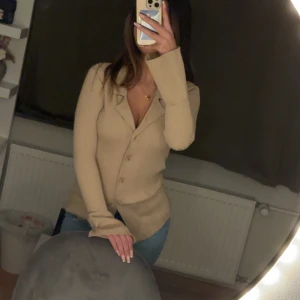 Beige kofta från Gina Tricot - Säljer en beige kofta från Gina i storlek XS. Koftan har en v-ringad design med knappar framtill och långa ärmar som går ut vid slutet. Säljer då jag fick denna men aldrig använt den då det inte riktigt är min stil🫶