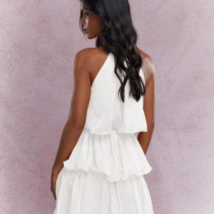 Vit ärmlös klänning med volanger - Säljer en vacker vit klänning med volanger och halterneck. Perfekt inför studenten🤩. Obs inte strykt på bilden så ännu snyggare då. Pris kan diskuteras!