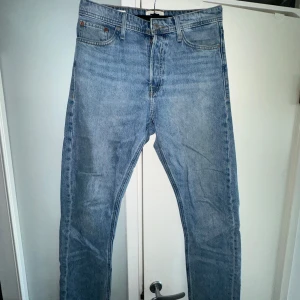 Blå jeansbyxor - Snygga blå jeansbyxor med klassisk design från Jack & Jones av modellen LOOSE/CHRIS. De har en knappgylf och bälteshällor, vilket gör dem perfekta för en avslappnad stil. Passar bra till både t-shirt och skjorta.