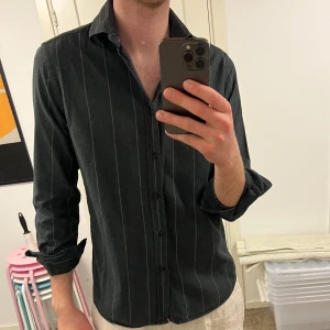 Svart randig skjorta - Snygg mörkgrå skjorta från Massimo Dutti med diskreta ränder. Perfekt både till vardags och på fest. Storlek M