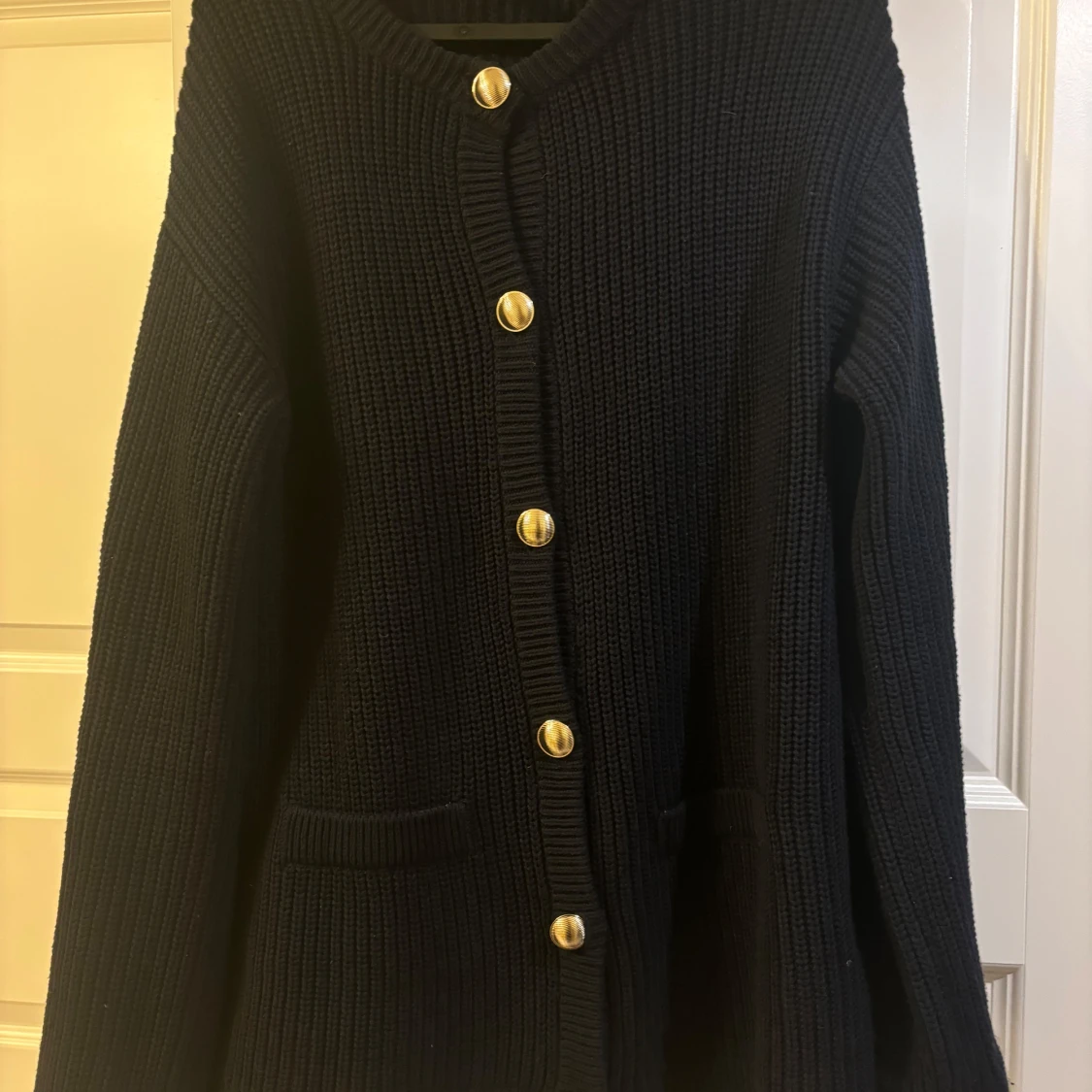 Svart stickad kofta med guldknappar