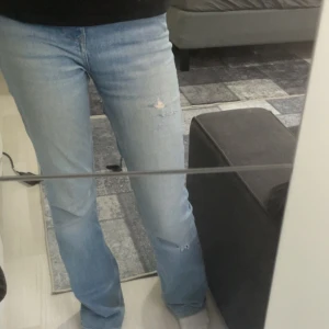 Ljusblå jeans med slitningar från Zara - Säljer ett par ljusblå jeans med slitningar på knäna. De har en klassisk femficksdesign och en bekväm passform. Perfekta för en avslappnad stil. Har 2 hål i bakfickorna också!!