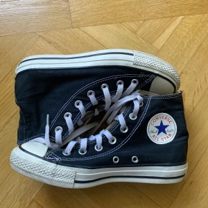 Svarta Converse All Star sneakers - Säljer ett par klassiska svarta Converse All Star sneakers med vit sula och snörning. Skorna har loggan på sidan och är i fint skick. Skorna är i storlek 37. 