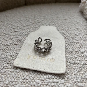 Silverfärgad ring från Yomie - Snygg silverfärgad ring från Yomie med en unik kedjedesign. Perfekt för att ge en stilren touch till din outfit. Ringen är justerbar och passar de flesta storlekar.