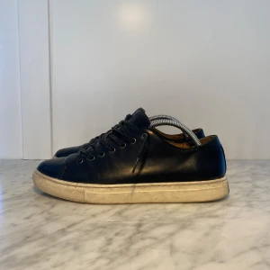 Svarta sneakers från Polo - Snygga svarta sneakers från Polo i skinn med klassisk snörning. Perfekta för en stilren look med en bekväm sula. Passar bra till både jeans och chinos. Bra använda men är fortfarande perfekta. Passar 42 och 43, priset är inte hugget i Sten🔥
