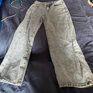 Blå jeansbyxor - Säljer ett par klassiska blå jeansbyxor med en avslappnad passform. Byxorna har en hög midja och vida ben, vilket ger en skön och trendig look. Perfekta för en casual stil.