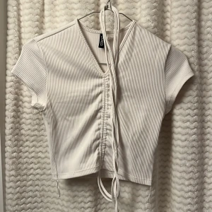 Vit ribbad topp från Divided H&M🤍 - Säljer en snygg vit ribbad topp från Divided. Med snören man kan göra en rosett.🥥
