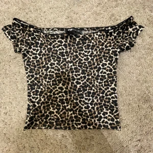 Leopardmönstrad offshoulder topp från FB Sister - Säljer en snygg leopardmönstrad offshoulder topp från FB Sister i storlek XS. Toppen har en liten rosett framtill och är perfekt för en trendig look. Materialet är mjukt och bekvämt.