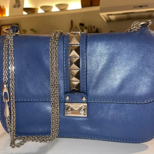 Valentino väska - Blå valentino väska i modellen ”Glam lock”, sjukt snygg men säljer då jag inte längre använder. Insidan är ganska smutsig och den har varit inlämnad för lagning en gång då fästet till kedjan lossnade (se bild). Köpt på Vestiaire, dustbag medföljer