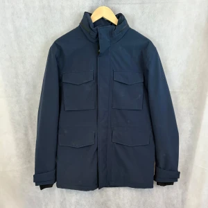 J.lindeberg field jacket  - Fint skick utöver defekten på bild 4. Skulle må bra av en tvätt. Modellen är 185 och bär M