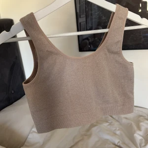 Beige ribbad linnetopp - Snygg beige ribbad linnetopp/croptop med breda axelband. Perfekt för en stilren och bekväm look.
