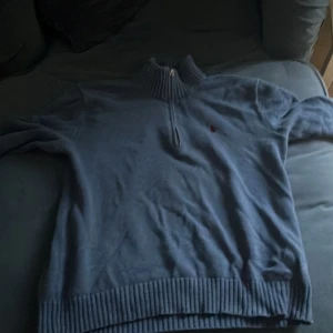 Blå tröja med dragkedja - Säljer en blå tröja med dragkedja och ribbad krage. Tröjan har långa ärmar och en liten logotyp på bröstet. Perfekt för kyliga dagar. Och det är en ralph lauren, det är en stolek s men den passar ochså m den är stor för att vara s  