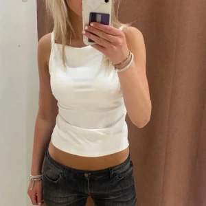 Vit ärmlös topp - Säljer en stilren vit ärmlös topp med rund halsringning. Perfekt för varma dagar eller som ett basplagg i garderoben. Enkel och tidlös design som passar till det mesta.