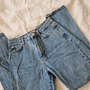 Blå jeans från Gina tricot - Snygga blå jeans från Gina tricot med klassisk femficksdesign och knappgylf. Perfekta för en avslappnad stil.