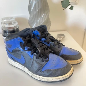 Nike Air Jordans i svart och blått - Säljer ett par klassiska Nike Air Jordans i svart och blått. Skorna har en ikonisk design med snörning och rund tå. Perfekta för sneaker-entusiaster som vill ha en stilren look. Kommer självklart att rengöras mer.
