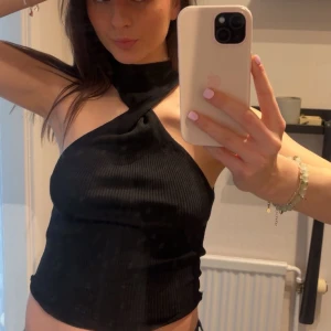 Svart ribbad oneshoulder topp - Snygg svart ribbad topp. Perfekt för en kväll ute eller en finare dag. Den har en unik omlottstil som är väldigt cool. 