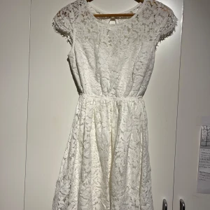 Vit spetsklänning - Säljer min student klänning . Använd 1 gång Elegant vit spetsklänning med korta ärmar och vackert blommönster. Klänningen har en öppen rygg och en feminin siluett som passar perfekt för speciella tillfällen. 