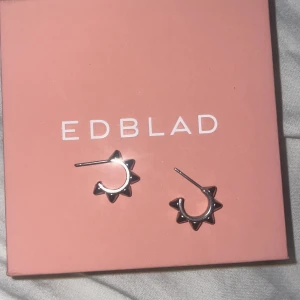 SMÅ Silverörhängen från Edblad - Snygga silverörhängen från Edblad i en unik stjärnformad design. Perfekta för att ge en edgy touch till din stil. Kommer i en fin rosa förpackning.