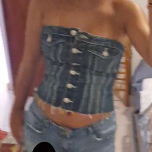 Jeans korsett-topp - Snygg jeans korsett-topp med knappar framtill och råa kanter. Perfekt för en trendig look. Axelbandslös design som ger en cool och avslappnad stil.