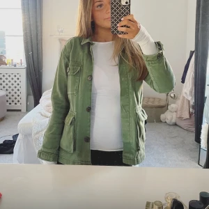 Grön jacka med knappar - Snygg grön jacka med knappar framtill och praktiska fickor. Perfekt för en avslappnad stil. Jackan har långa ärmar och en normal passform.