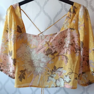 Gul blommig topp från H&M - Säljer en gul blommig topp från Hm. Öppen rygg med knytning. Helt oanvänd och lappen finns kvar. Priset kan diskuteras!! 