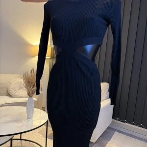 Svart ribbad klänning - Snygg svart ribbad klänning med lång ärm och en tight passform. Klänningen har en unik design med korsade detaljer i midjan som ger en modern look. Perfekt för en stilren och elegant outfit. Passar perfekt som oversize modell (s/m/l storlek). 🌸👌👌