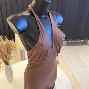 Brun axelbandslös klänning - Snygg brun klänning med djup v-ringning och axelbandslös design. Perfekt för en kväll ute eller en speciell tillställning. Klänningen har en smickrande passform som framhäver figuren. Passar perfekt i s/m/l storlek.🌸