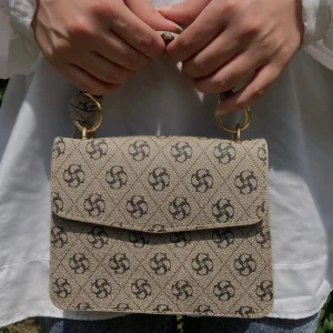 Beige mönstrad axelväska - Snygg beige axelväska. Går att använda med eller utan rep. Oanvänd.