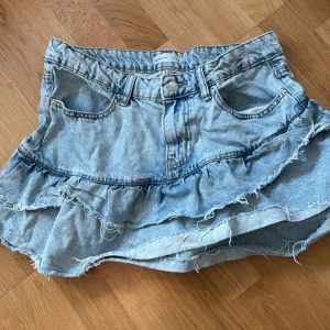 Lågmidjad jeanskjol från Gina tricot  - Jätte fin jeans kjol med volanger från Gina tricot köpt förra sommaren endast använd en gång och är i jätte bra skick💕