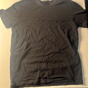 Svart t-shirt från Calvin Klein Jeans - Snygg svart t-shirt från Calvin Klein Jeans med diskret logga på kragen. Perfekt för en stilren look. Tillverkad i mjukt material för extra komfort.