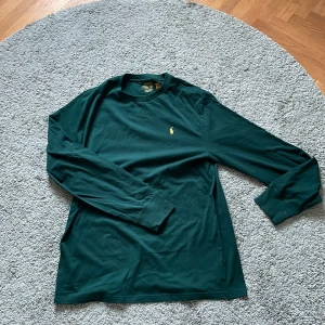 Grön långärmad tröja från Ralph Lauren - Säljer en stilren grön långärmad tröja från Ralph Lauren med det klassiska broderade logotypen på bröstet. Perfekt för en avslappnad och snygg look. Tröjan är tillverkad i ett mjukt och bekvämt material. Perfekt nu till våren! Nypris: 950 kr