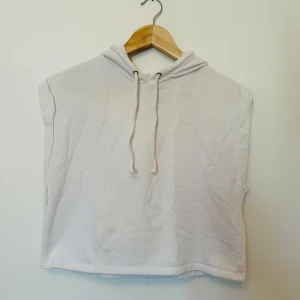 Vit ärmlös hoodie från H&M - Säljer en vit ärmlös hoodie från H&M. Den har en avslappnad passform med dragsko i huvan. Perfekt för träning eller i vardagen.