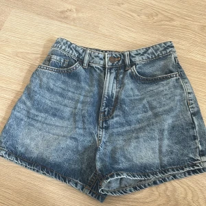 Blå jeansshorts från Lindex - Säljer ett par klassiska blå jeansshorts från Lindex i storlek XS. De har en hög midja och en knapp- och dragkedjestängning framtill. Perfekta för sommardagar!