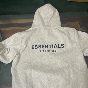Ljusgrå Essentials Fear of God hoodie - Säljer en ljusgrå hoodie från Essentials Fear of God i storlek M. Tröjan har stor svart logga på ryggen och mindre logga på bröstet.  Bra pris äkta och sprillans ny pris kan diskuteras 