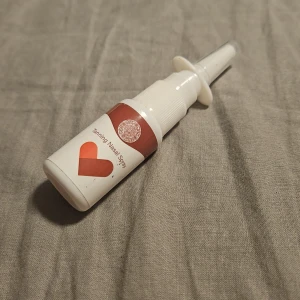 Tanning Nasal Spray med hjärtmotiv - Tanning Nasal Spray i vit plastflaska med röd etikett och hjärtmotiv. Flaskan har en smidig spraytopp för enkel applicering. Perfekt för dig som vill ha en solkysst look utan att använda traditionella brun utan sol-produkter.