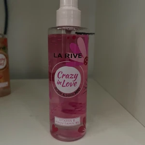 La Rive Crazy in Love Body Mist - Fräsch body & hair mist från La Rive i doften Crazy in Love. Flaskan är genomskinlig med rosa vätska och dekorerad med hjärtan och blommor. Innehåller vitamin E och provitamin B5 för extra vård till hud och hår. Perfekt för en snabb uppfräschning.