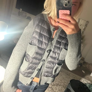 Grå dunväst/cardigan från Moncler - Säljer en grå dunväst/cardigan från Moncler med stickade ärmar och quiltad front. Storlek L men passar bättre XS-S💞