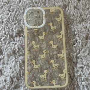 Genomskinligt mobilskal med ankor - Sött genomskinligt mobilskal med gulliga gula ankor och texten 'DUCKLING' runt kanterna. Skalets design är lekfull och passar perfekt för dig som vill ha något unikt och charmigt till mobilen.