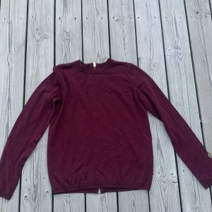 Vinröd kofta med dragkedja i ryggen från STOCKH LM - Snygg kofta från STOCKH LM i storlek XS. Koftan har en hel dragkedja i guld baktill som ger en cool detalj. Tröjan är vinröd glittrig. 