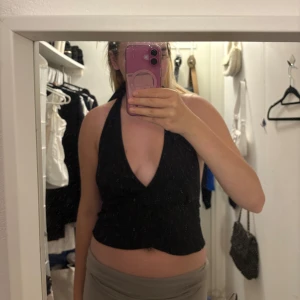 Svart omlott halterneck topp storlek M men passar L med - Säljer en svart halterneck topp med djup v-ringning och omlott-design. Toppen är croppad och knyts i nacken, vilket ger en snygg och trendig look. Perfekt för dig som gillar stilrena och enkla plagg med en twist. Storleken är M men passar storlek L med 