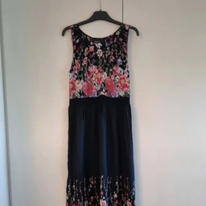 Blommig långklänning från KappAhl - En lång klänning i svart med blommor,  sparsamt använd. Storlek på lappen 40 men jag tycker den är mer som en 38. Klänningen har resår i midjan under bröstet och även ett resår i v-ringningen samt en liten dragkedja i sidan. Längd cirka 127 cm lång. INFO: Hund finns i hemmet. 