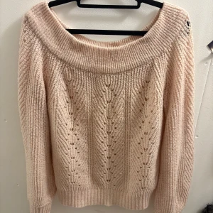 Ljusrosa stickad offshoulder tröja - Superfin ljusrosa stickad tröja från Gina Tricot med bred offshoulder-ringning och snyggt hålmönster framtill. Tröjan har långärmade ribbade muddar och en loose passform som ger en chill vibe. Perfekt att styla med jeans eller kjol för en trendig look.