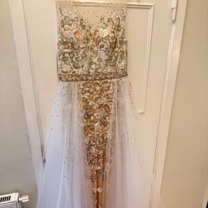 Glittrig långklänning med spets och pärlor - Långklänning från Chiccy med glittriga pärlor och broderad spets i silver och guld. Strl 42 men passar även 40. Pris kan diskuteras 