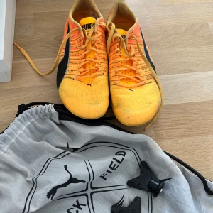 Puma Evospeed Tokyo BRUSH spikskor - Säljer ett par Puma Evospeed Tokyo BRUSH spikskor i orange och gul med svarta detaljer. Ovandelen är i lätt syntetmaterial med snörning och ventilerande mesh. Sulan har metallspikar för max grepp på löparbanan. Perfekta för friidrott och sprint.