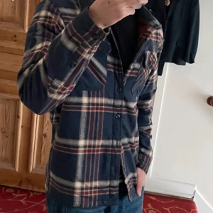 Rutig overshirt från Patagonia - Snygg rutig overshirt från Patagonia i mörkblått, vinrött och beige. Skjortan har två bröstfickor med knappar, klassisk krage och är tillverkad i mjuk bomull. Perfekt att slänga över en t-shirt för en chill look. Men även varm och bra anpassad för höst och tidig vinter. Nypris 2500. Pris kan diskuteras