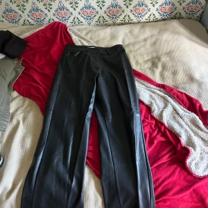Svarta skinnbyxor från Madlady - Säljer ett par svarta skinnbyxor från Madlady i storlek S. Byxorna har raka ben och klassisk passform med fickor fram och dragkedja. Perfekta för dig som vill ha en edgy look och gillar trendiga material.