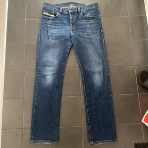 Blå jeans från Diesel straight fit - Säljer ett par klassiska blå jeans från Diesel med raka ben och normal passform. Jeansen har snygg tvätt framtill, fem fickor och läderpatch med Diesel-logga bak i midjan. Tillverkade i slitstarkt denimtyg som ger en tidlös look.