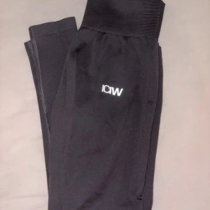 Svarta seamless tights från ICANIWILL - Svarta seamless tights från ICANIWILL med hög midja och diskret logga på låret. Tillverkade i stretchigt material med 92% nylon och 8% spandex, perfekta för träning eller chill. Snygg passform som sitter på plats hela dagen.