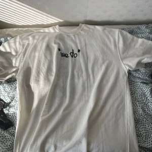 Vit t-shirt med tryck från Zara - Vit t-shirt från Zara med coolt svart tryck framtill där det står "we do" och en stor grafisk illustration med texten "Nothing" på ryggen. Klassisk passform och rund hals. Tillverkad i mjuk bomull, perfekt för en avslappnad streetstyle.